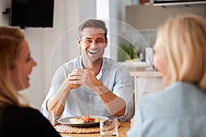 Family With Senior Mother And Adult Offspring Eating Brunch Around Table At Home Together