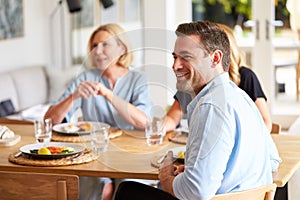 Family With Senior Mother And Adult Offspring Eating Brunch Around Table At Home Together