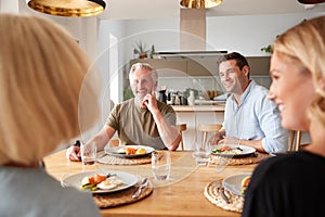 Family With Senior Parents And Adult Offspring Eating Brunch Around Table At Home Together