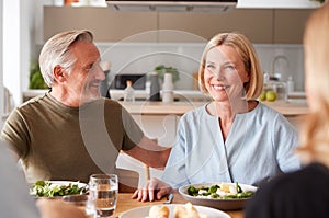 Family With Senior Parents And Adult Offspring Eating Meal Around Table At Home Together