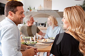 Family With Senior Parents And Adult Offspring Eating Meal Around Table At Home Together