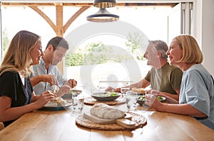 Family With Senior Parents And Adult Offspring Eating Meal Around Table At Home Together photo