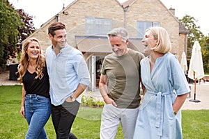 Family With Senior Parents And Adult Offspring Walking And Talking In Garden Together