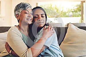 Family, senior woman hugging her daughter and love with people sitting on a sofa in the home living room during a visit