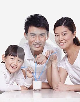 Family sharing a glass of milk, studio shot