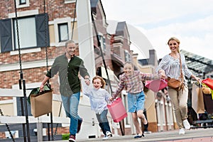 Family with shopping bags holding hands and walking while shopping