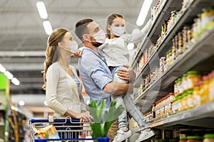 Family with shopping cart in masks at supermarket