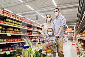 Family with shopping cart in masks at supermarket