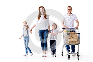 happy young family with two kids walking with shopping trolley