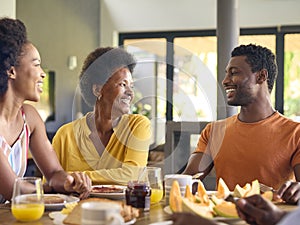 Family Shot With Senior Parents And Adult Offspring At Breakfast Around Table At Home