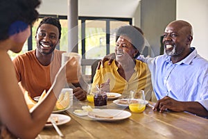 Family Shot With Senior Parents And Adult Offspring At Breakfast Around Table At Home