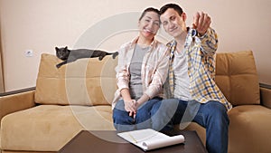 Family shows keys sitting with cute cat on sofa in room