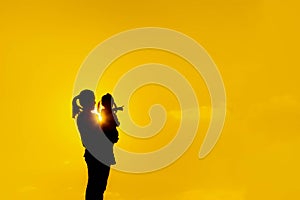 The family silhouette of the mother and child standing watch the sunset and the sky in orange in evening