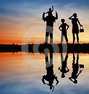 Family silhouette on sunset sky.