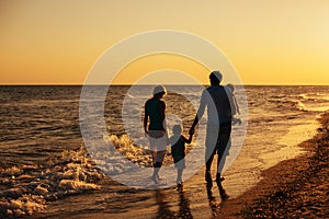 Family silhouettes on beach at sunset