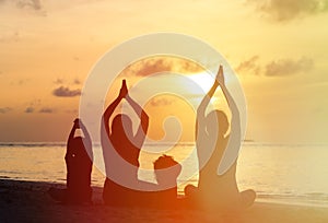 Family silhouettes doing yoga at sunset