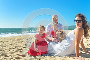Family with sisters in red dress and dog on the beach