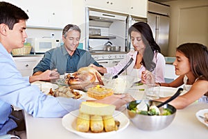 Family Sitting Around Table Saying Prayer Before Eating Meal