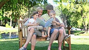 Family sitting on a bench reading a book