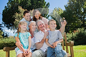 Family sitting on a bench taking photo of themselves