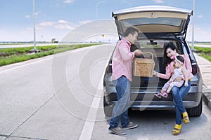 Family sitting in car with picnic basket