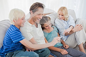 Family sitting on a couch and looking at a photo