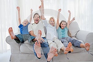 Family sitting on a couch and raising arms