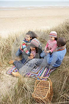 Family Sitting In Dunes Enjoying Picnic