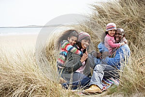 Family Sitting In Dunes Enjoying Picnic On Winter