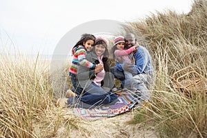 Family Sitting In Dunes On Winter Beach