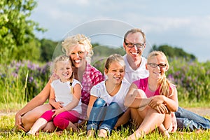 Family sitting on grass in lawn or field