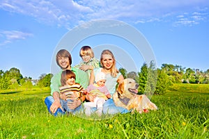Family sitting on green grass with dog