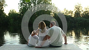 Family sitting on lake surrounded by green nature