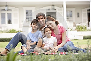 Family Sitting Outside House On Lawn photo