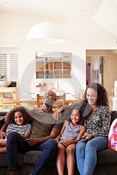 Family Sitting On Sofa At Home And Watching Movie On TV Together