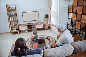 Family Sitting On Sofa At Home Watching TV Together