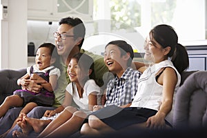 Family Sitting On Sofa At Home Watching TV Together