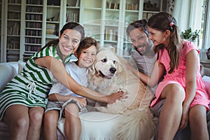 Family sitting on sofa with pet dog in living room