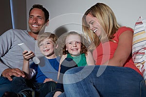 Family Sitting On Sofa Watching TV Together