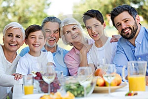 Family sitting at table outdoors, smiling