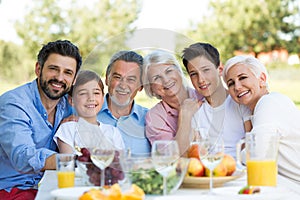 Family sitting at table outdoors, smiling