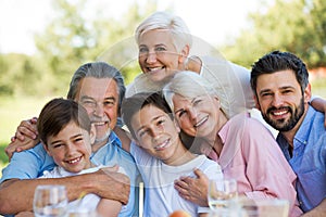 Family sitting at table outdoors, smiling