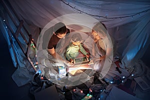 Family sitting in a teepee, reading stories with the flashlight