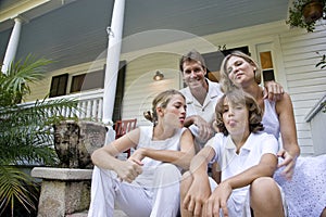 Family sitting together on front porch steps