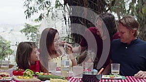 Family sitting together at table, hugging, smiling and talking