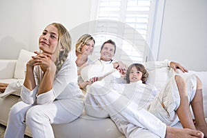 Family sitting together on white sofa watching TV