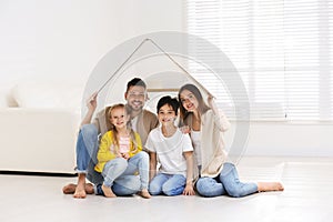 Family sitting under cardboard roof at home. Insurance concept