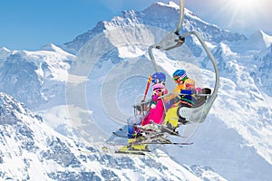 Family in ski lift in mountains. Skiing with kids