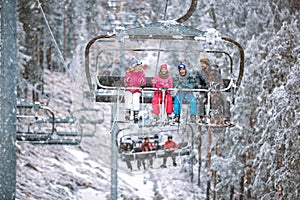 Family skier and snowboarder lifting on the chairlift at ski res photo