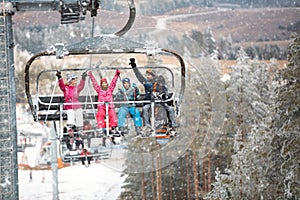 family skier and snowboarder riding up to the top of the mountain on ski lift